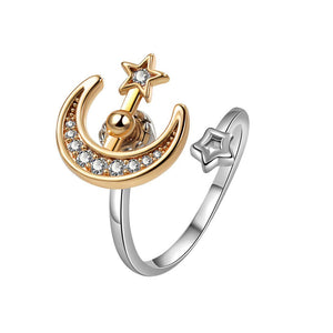 Gold and silver spinner ring with moon and star design on a white background