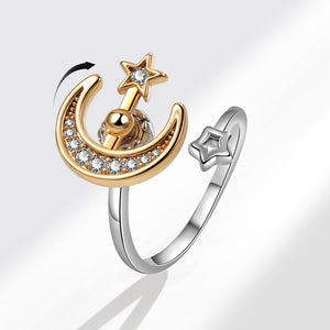 Gold and silver spinner ring with moon and star design on a white background