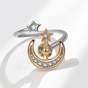 Gold and silver spinner ring with moon and star design on a white background