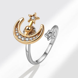 Gold and silver spinner ring with moon and star design on a white background