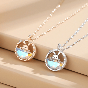 Two necklaces with round pendants featuring cartoon characters on a beige surface.