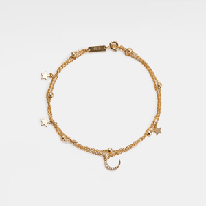 Gold bracelet with star and moon charms on a light gray background