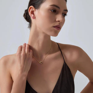 Woman wearing a gold necklace against a plain background