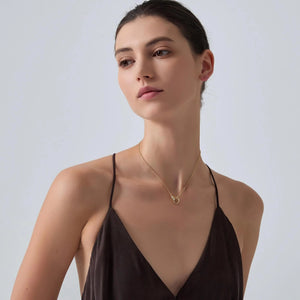 Woman wearing a gold necklace against a plain background