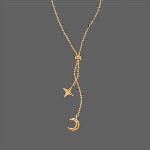 Gold necklace with star and moon pendants on a gray background