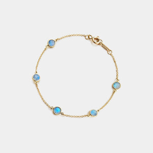 Gold bracelet with blue gemstones on a light gray background