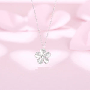 Flower-shaped silver pendant on a pink satin background