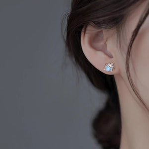 Close-up of an ear wearing a silver earring with a gemstone on a dark background
