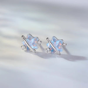 Pair of butterfly-shaped earrings with opal stones on a light gray background