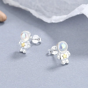 Silver astronaut earrings with a star on a gray surface
