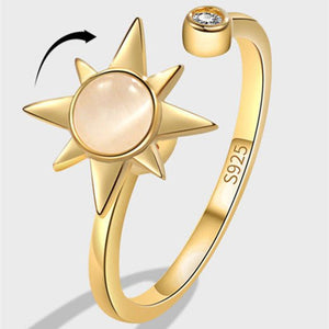 Gold spinner ring with star design and gemstone on a light gray background