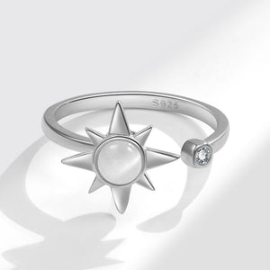 Silver spinner ring with star design and gemstone on a light gray background
