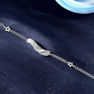 Two silver bracelets with star and moon designs, one with a leaf-like charm, displayed against a dark, sparkly background.
