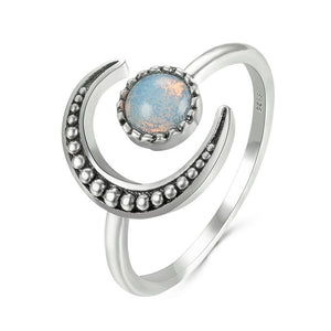 A silver-colored stacking ring with a crescent moon shape and a moonstone in the center, displayed on a white background.