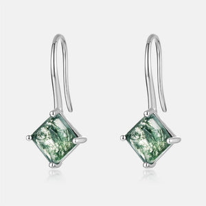 Silver earrings with green gemstones on a white background