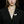 Woman wearing a black blazer with a butterfly brooch on a black background