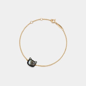 Gold bracelet with a black cat-shaped charm on a white background