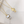 Two gold necklaces with pearl pendants on a white surface