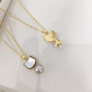 Two gold necklaces with pearl pendants on a white surface