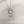 Cat-shaped pendant with a pearl on a gold chain against a white background