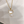 Gold necklace with a cat-shaped pendant and pearl on a white background