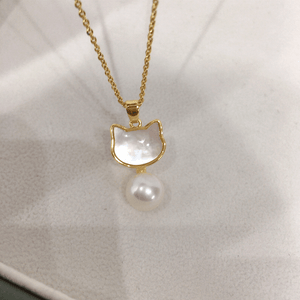 Gold necklace with a cat-shaped pendant and pearl on a white background