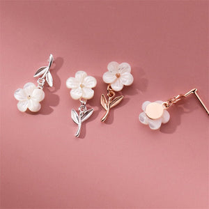 Set of floral earrings with metallic and rose gold finishes on a pink background