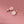A set of sterling silver earrings with mother of pearl inlays designed to resemble cherry blossoms, displayed against a pink background.