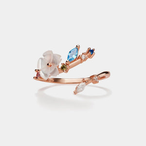 Rose gold ring with gemstones on a light gray background