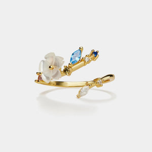 Gold ring with floral design and gemstones on a white background