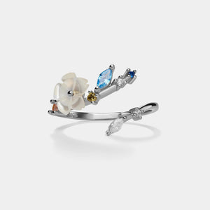 Silver ring with floral design and gemstones on a white background