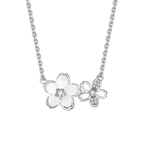 A silver necklace with two cherry blossom pendant charms, one featuring a mother of pearl center.