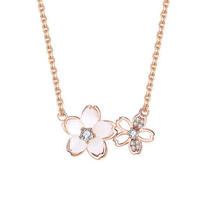 A silver necklace with two cherry blossom pendant charms, one featuring a mother of pearl center.