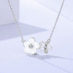 Silver necklace with floral pendant on a light blue background