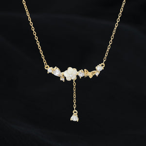 Gold necklace with floral design and pendant on a black background