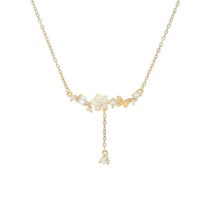 Delicate gold necklace with floral and butterfly pendants on a white background