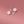 Floral earrings with pearl-like flowers and silver leaves on a pink background