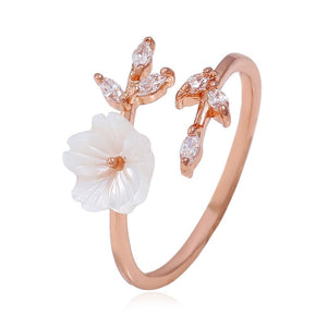 An adjustable ring with a gold plating, featuring a mother of pearl flower bypass design with cubic zirconia accents.