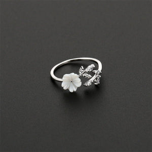 An adjustable ring with a gold plating, featuring a mother of pearl flower bypass design with cubic zirconia accents.