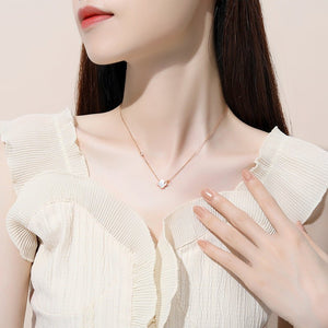 Woman wearing a delicate gold necklace with a heart pendant, touching her chest.