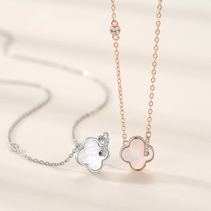 Two silver necklaces with clover-shaped pendants on a light beige background