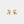 Gold earrings with white stones on a light gray background