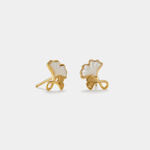 Gold earrings with white stones on a light gray background