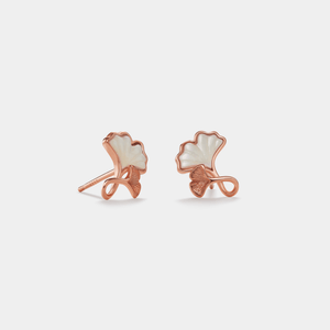 Pair of rose gold earrings with white stones on a light gray background