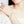 Model wearing a pearl bracelet with gold starfish and shell charm on a light beige background