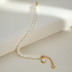 Pearl bracelet with gold starfish and shell charm on a light beige background