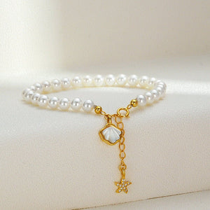 Pearl bracelet with gold starfish and shell charm on a light beige background