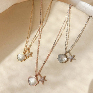 Three necklaces with starfish and shell pendants on a beige surface
