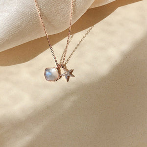 A collection of three mother of pearl seashell starfish necklaces with gold plating, displayed on a beige fabric surface.