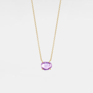 Gold necklace with a purple gemstone on a light gray background
